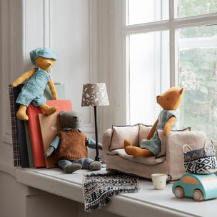Maileg Toy bears and a car on a windowsill with a lamp and books in the background