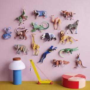 Colorful animal figurines on a pink wall with toys on a yellow surface