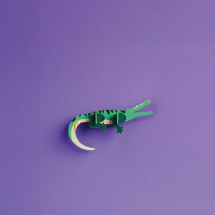 Green paper crocodile on a purple background