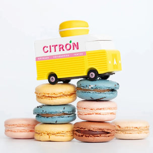 A Candylab wooden toy Citron Macaron van placed on a pile of macaron | Conscious Craft