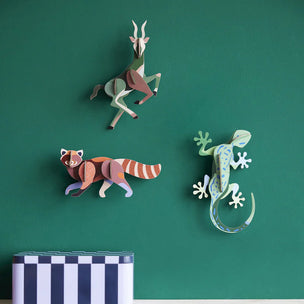Three 3D paper animal wall decorations on a green wall with a striped box at the bottom.