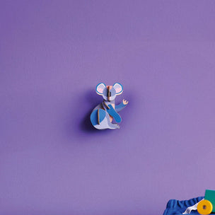 Blue cartoon character on a purple wall with toys on a green surface below.