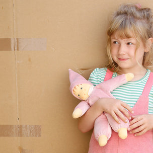 Child holding a pink plush toy against a cardboard box background