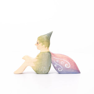 Eric & Albert wooden toy fairy in green sitting on the ground with pinky purple wings | © Conscious Craft