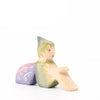 Eric & Albert wooden toy fairy in green sitting on the ground with pinky purple wings | © Conscious Craft