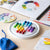 Colorful round board with beads on a table next to a color wheel and design books.