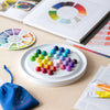 Colorful round board with beads on a table next to a color wheel and design books.