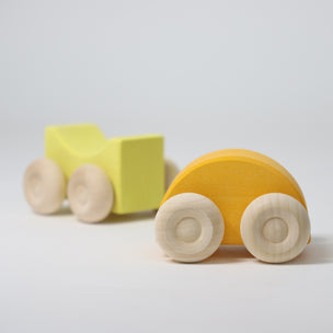 Wooden toy truck with a yellow bed and orange body on a light gray background
