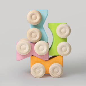 Colorful toy block with wooden wheels on a light gray background