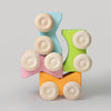 Colorful toy block with wooden wheels on a light gray background