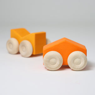 Grimm's Two orange wooden toy cars with beige wheels on a light gray background