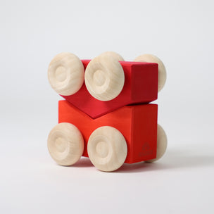 Red wooden toy cars with beige wheels on a white background