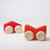 Grimm's Two red wooden toy cars with beige wheels on a white background