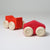 Grimm's Two red wooden toy cars with beige wheels on a light gray background