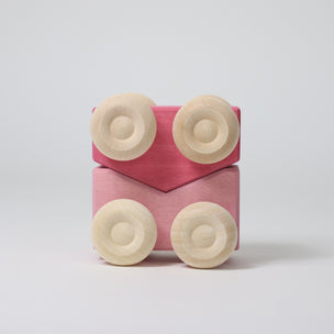 Grimm's Pink toy car with beige circular pieces on a light gray background
