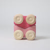 Grimm's Pink toy car with beige circular pieces on a light gray background