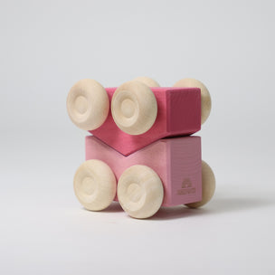 Pink wooden toy car with wheels on a light gray background