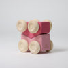 Pink wooden toy car with wheels on a light gray background