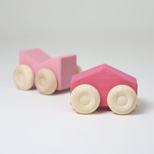 Grimm's Two pink wooden toy cars on a white background
