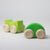 Grimm's Two green wooden toy cars on a light gray background