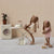 Two maileg bunnies in a domestic setting with a washing machine and ironing board.