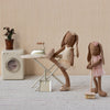 Two maileg bunnies in a domestic setting with a washing machine and ironing board.
