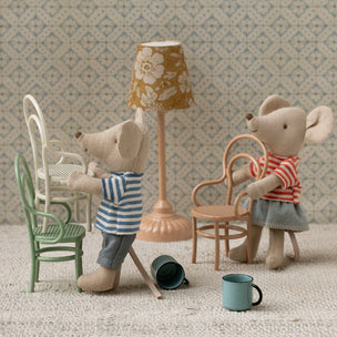 Two toy mice in a miniature room with furniture and decor.