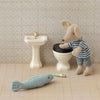 Miniature bathroom set with a toy mouse on a toilet, sink, and fish toy on a tiled floor.