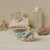 Maileg Miniature bedroom scene with a bed, toys, and furniture on a textured surface.