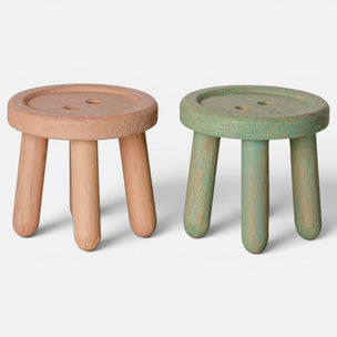 Two Maileg small round wooden stools with four legs, shown on a light gray studio background. The stool on the left is natural light wood, and the stool on the right has a distressed sage green finish.