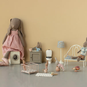 Children's playroom with Maileg toy furniture and stuffed animals on a beige wall background