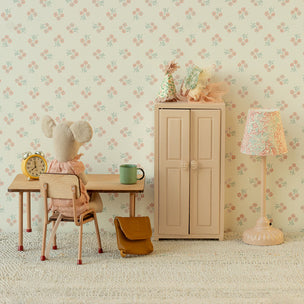 Children's room with floral wallpaper, desk, chair, cabinet, and lamp.