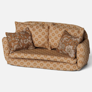 A miniature fabric Maileg mice dollhouse sofa with a floral pattern in tan and brown, featuring two matching decorative throw pillows, shown against a plain light gray background.