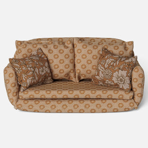 A vintage-style upholstered loveseat Maileg Mice sofa in a warm tan and brown floral pattern, featuring two matching floral throw pillows, photographed against a plain light gray background.