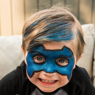 Child with blue superhero mask on a light-colored couch