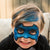 Child with blue superhero mask on a light-colored couch