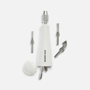 A white and silver linocut tool with various metal and white attachment heads, displayed on a clean light gray background. The main body features the black text 'RICO DESIGN'.