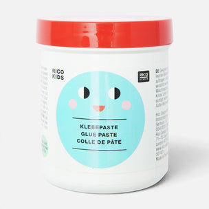 A white plastic tub of Rico Kids Klebebaste Glue Paste with a bright red lid and a light blue smiley face label, shown on a clean white background.