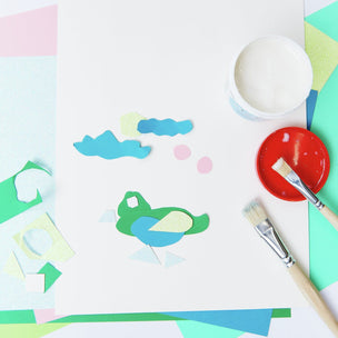 Colorful painting project with a frog design on paper, paintbrushes, and paint containers.