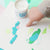 Child's hand interacting with colorful paper cutouts on a light surface