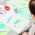 Child engaged in art project with colorful paper shapes and paint on a table.