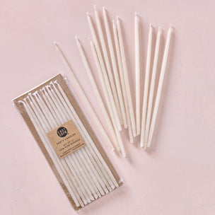 Set of white candles with packaging on a pink background
