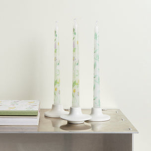 Three floral-patterned candles on a metallic surface with a light background