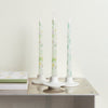 Three floral-patterned candles on a metallic surface with a light background