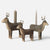 Three hand-carved wooden Maileg reindeer candle holders with antlers, arranged in a group on a light gray background. Two reindeer hold taper candles, and one holds a pillar candle.