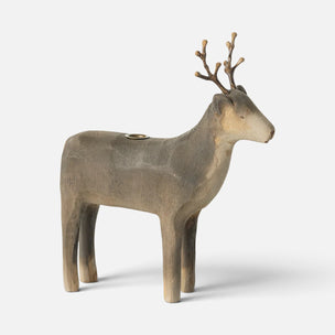 A sculptural Maileg deer figurine in a weathered taupe-brown finish with a small brass candle holder inset on its back, shown against a plain light gray background.