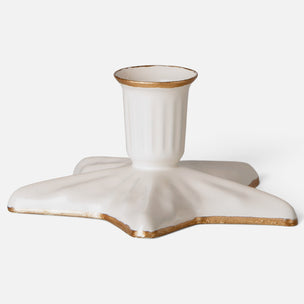 A ceramic candle holder with a star-shaped base and a fluted cup, finished in off-white with a metallic gold glaze accent.