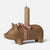 A rustic Maileg wooden pig-shaped candle holder with a lit beige pillar candle inserted into its back. The pig is decorated with a red and white gingham ribbon bow around its neck and features the brand name 'Rustic Hay' printed on its side.