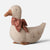 A plush fabric Maileg goose decoration with a beige body, brown beak and feet, and a red patterned bow around its neck, photographed on a light gray background.