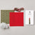 Craft kit components laid out on a light gray background, including olive green patterned felt, a red felt square with black teardrop outlines, a bundle of red, beige, and green striped thread, white stuffing, a needle, and an instruction booklet.